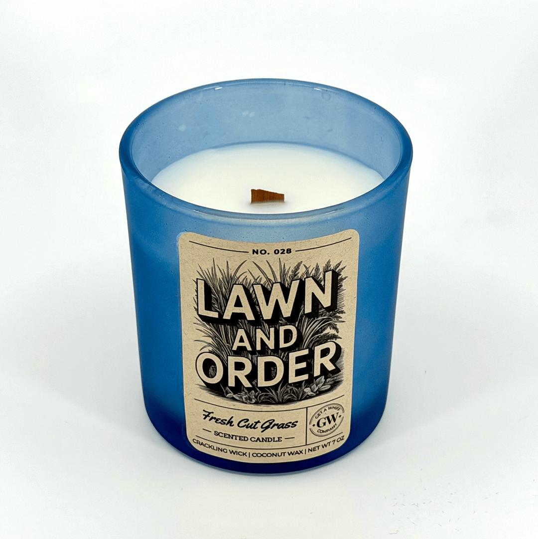 Candle with a blue glass container and 'Lawn and Order' label on a white background