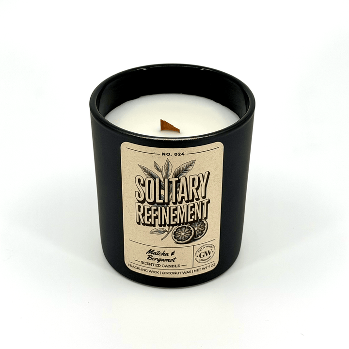 Black candle with a beige label on a white background