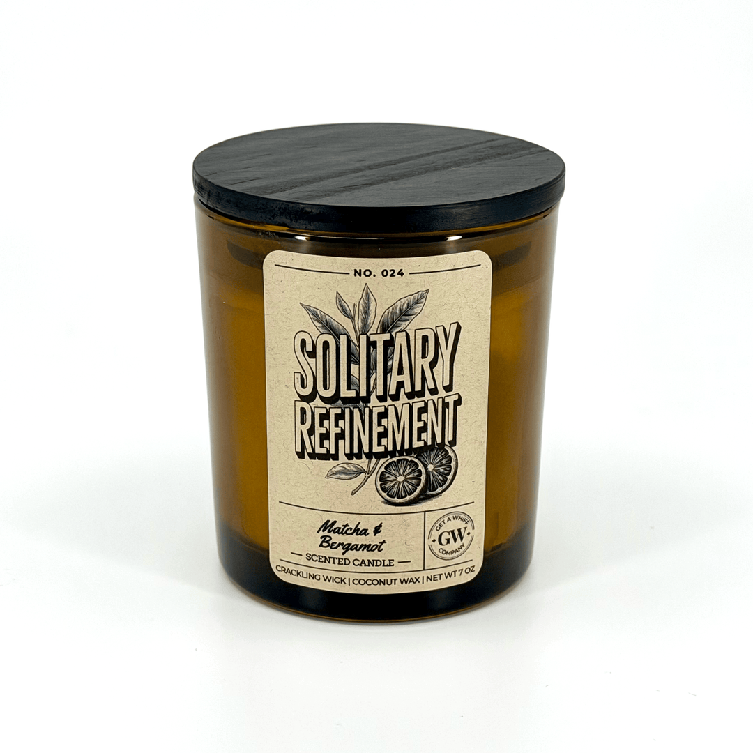Scented candle in a brown jar with a black lid on a white background
