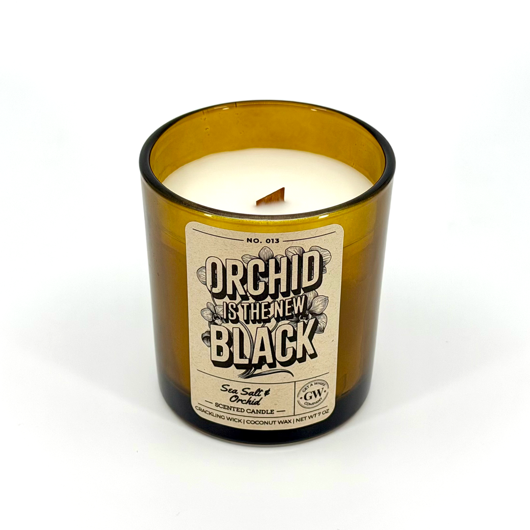 Candle in a brown glass container with a label on a white background