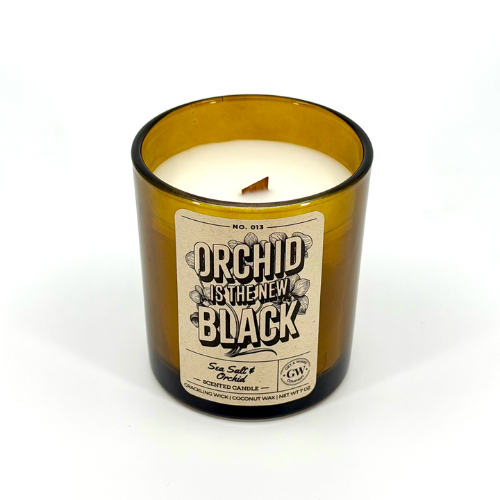 Candle in a brown glass container with a label on a white background